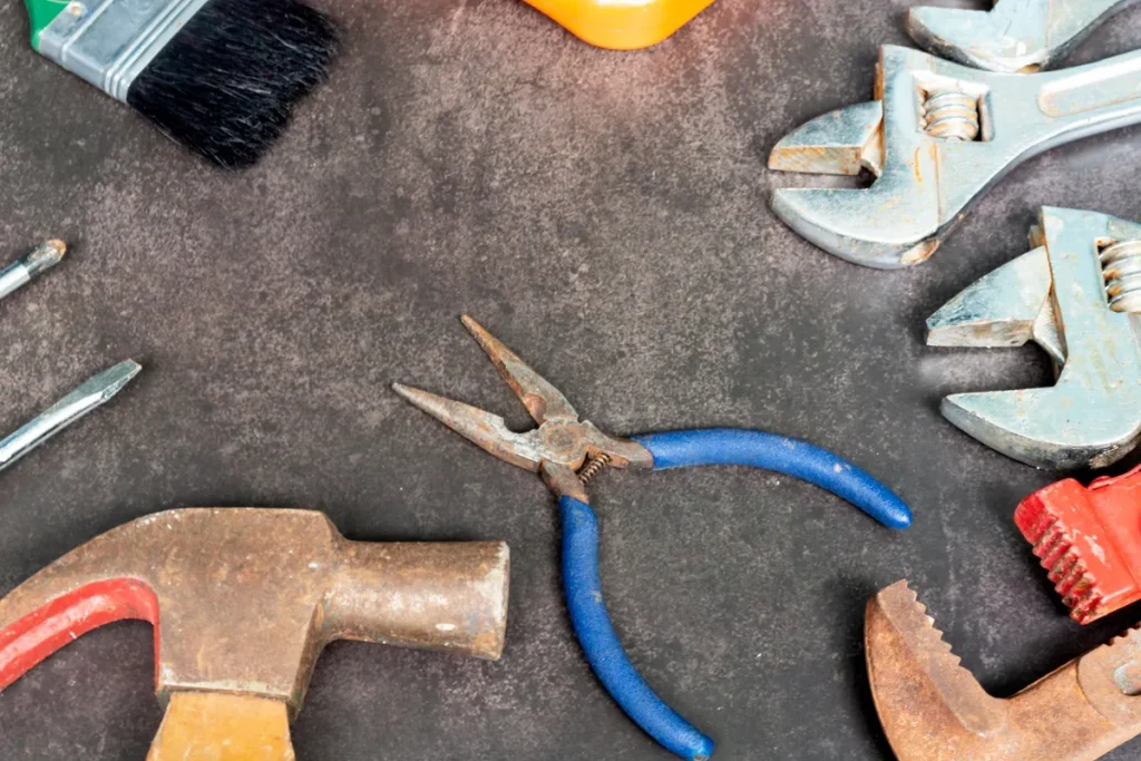 Old plumbing tools scattered on a concrete floor, highlighting the importance of local repair services.