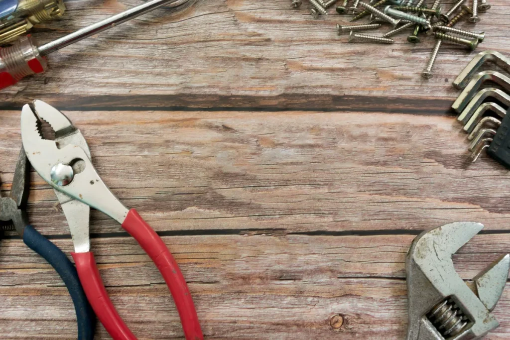 Old plumbing tools scattered on a wooden floor, highlighting the importance of reliable repairs in neighborhoods.